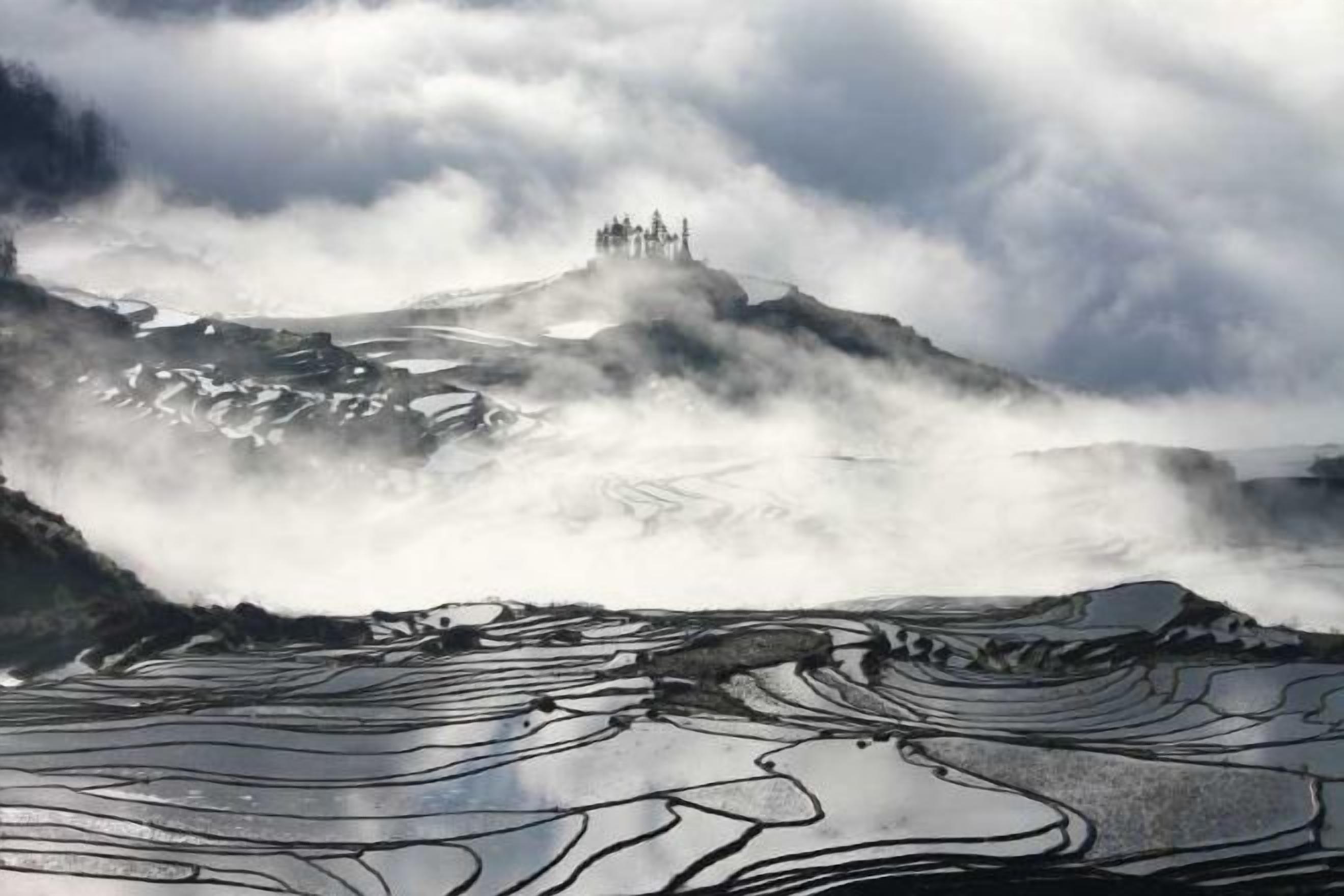 Un castillo en la cima de una montaña rodeado de nubes.