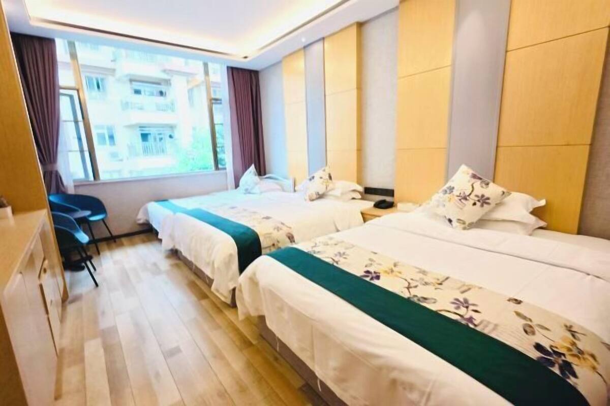 A hotel room with two beds, a desk, and a window with curtains.