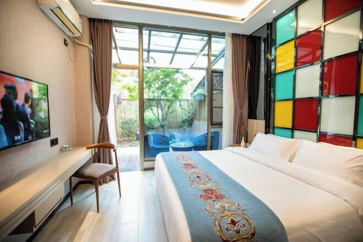 A hotel room with a bed, a TV, a desk, and a chair.