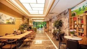 A hotel lobby with a long reception desk, multiple seating areas, and a large wall with a bookshelf and a painting. - Hongting Garden Hotel (Kunming)