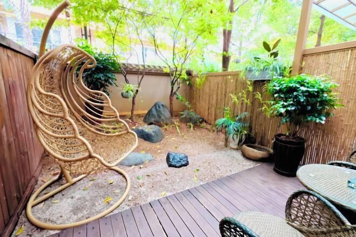 A wooden deck with a wicker chair, potted plants, and a small table.