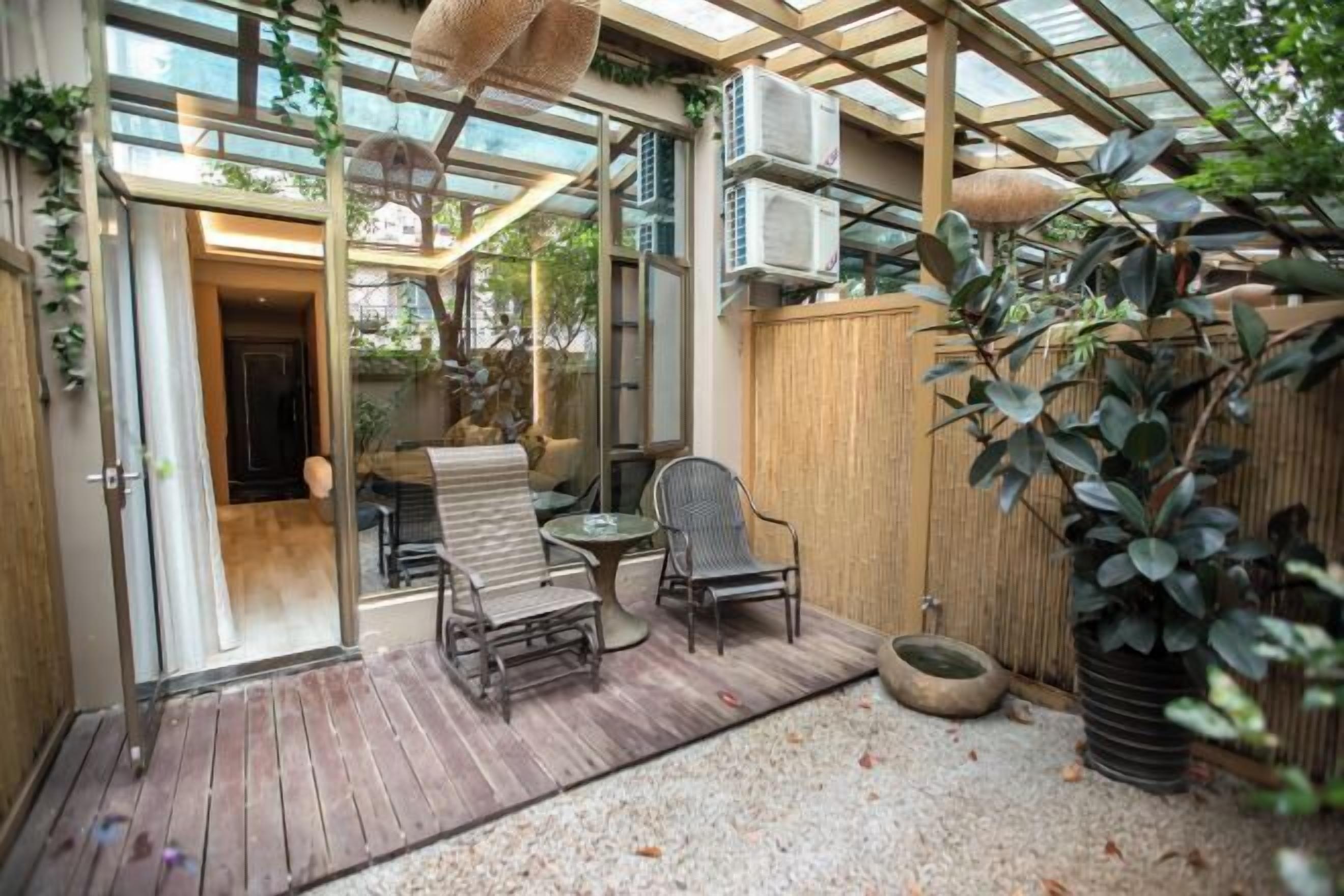 A covered patio with a wooden deck, a glass door leading inside, and a seating area with chairs and a table.