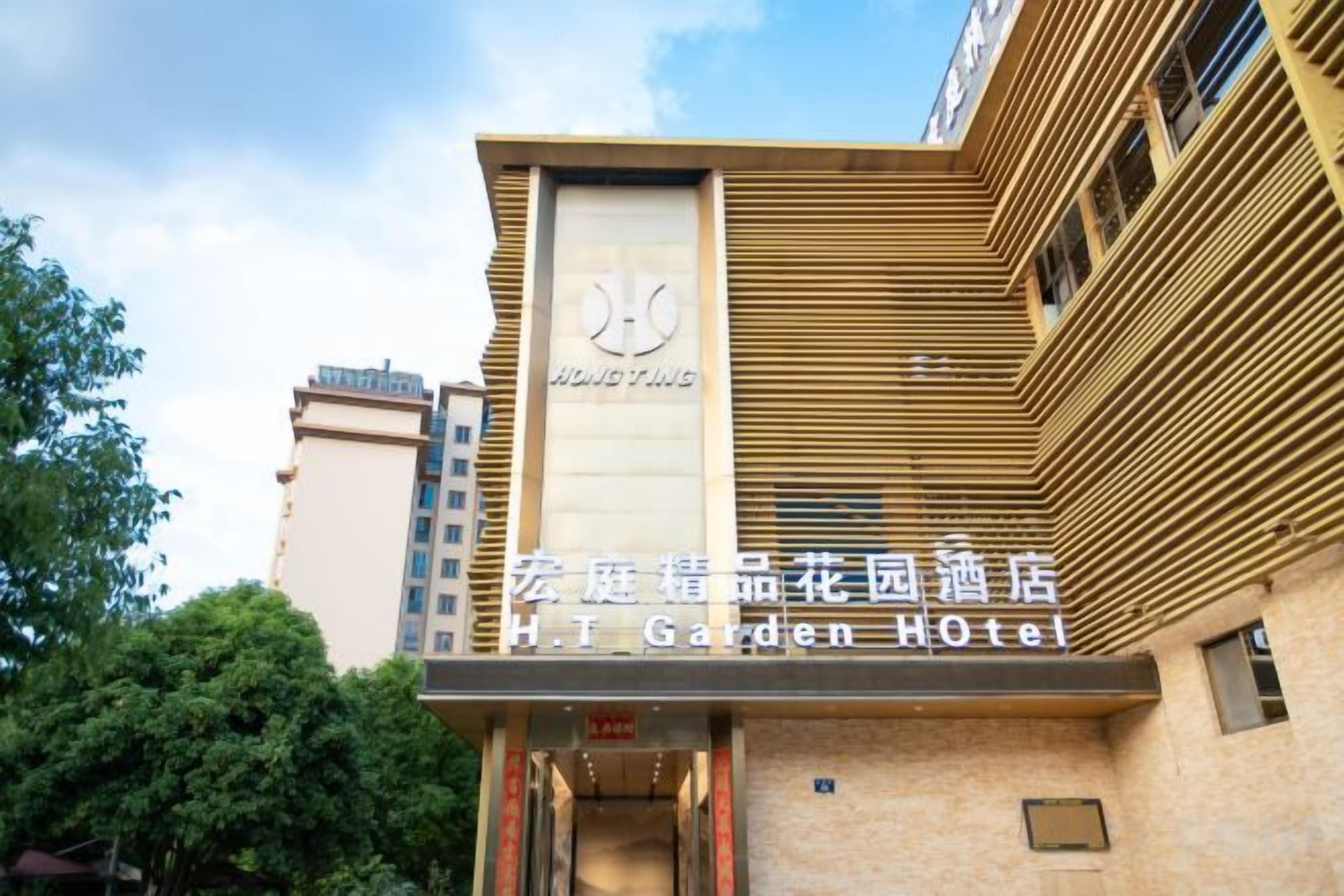 A hotel with a modern facade, a prominent logo, and a sign indicating it's the H. T. Garden Hotel.