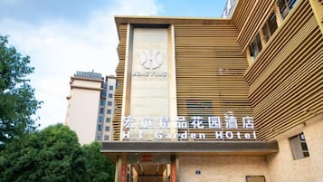 Un hotel con fachada moderna, un logotipo destacado y un cartel que indica que es el H. T. Garden Hotel.