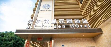 The exterior of the Garden Hotel with a prominent sign and a clock above the entrance.