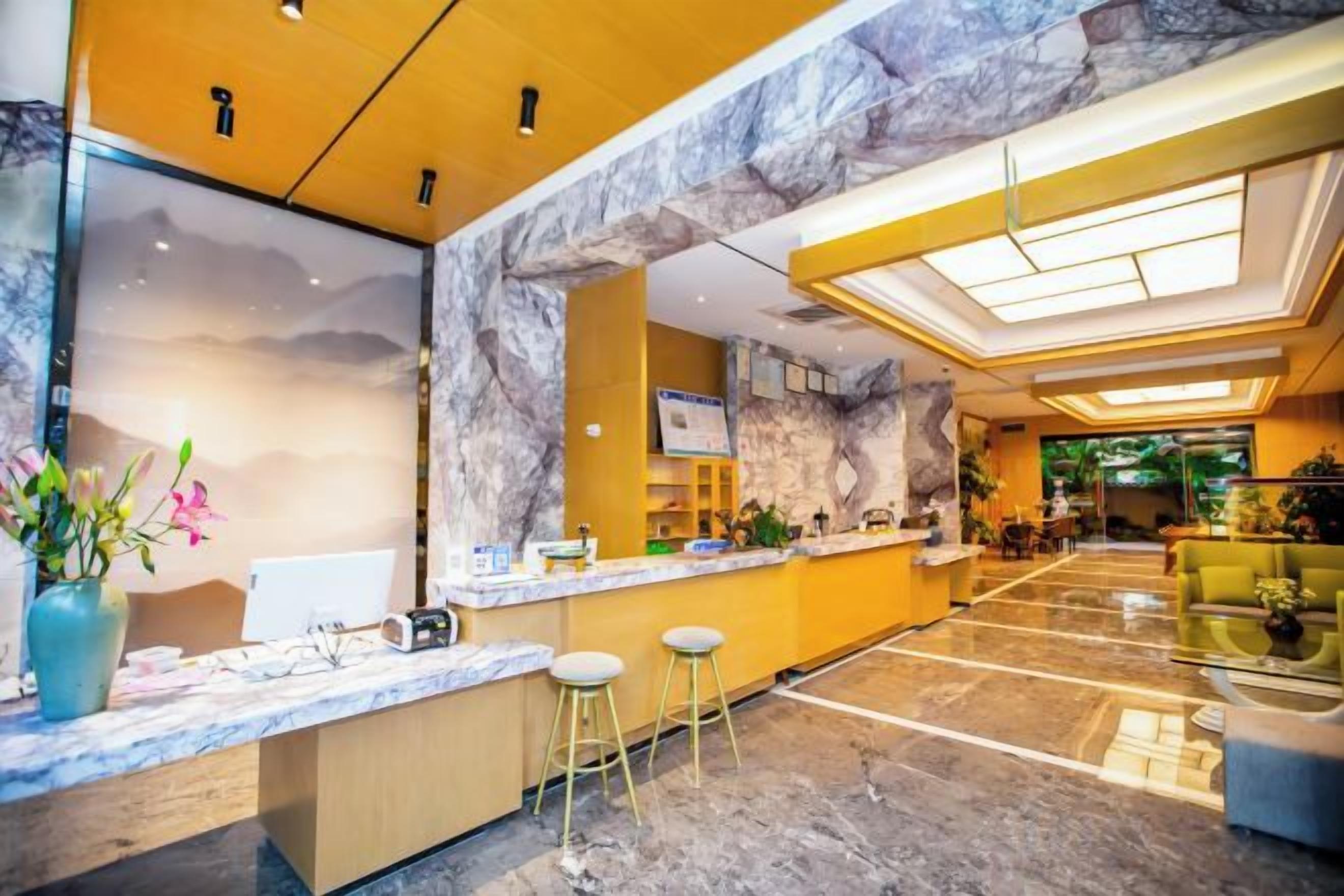 Et hotellobby med en receptionsdisk i marmor, et siddeområde og et stort vindue.