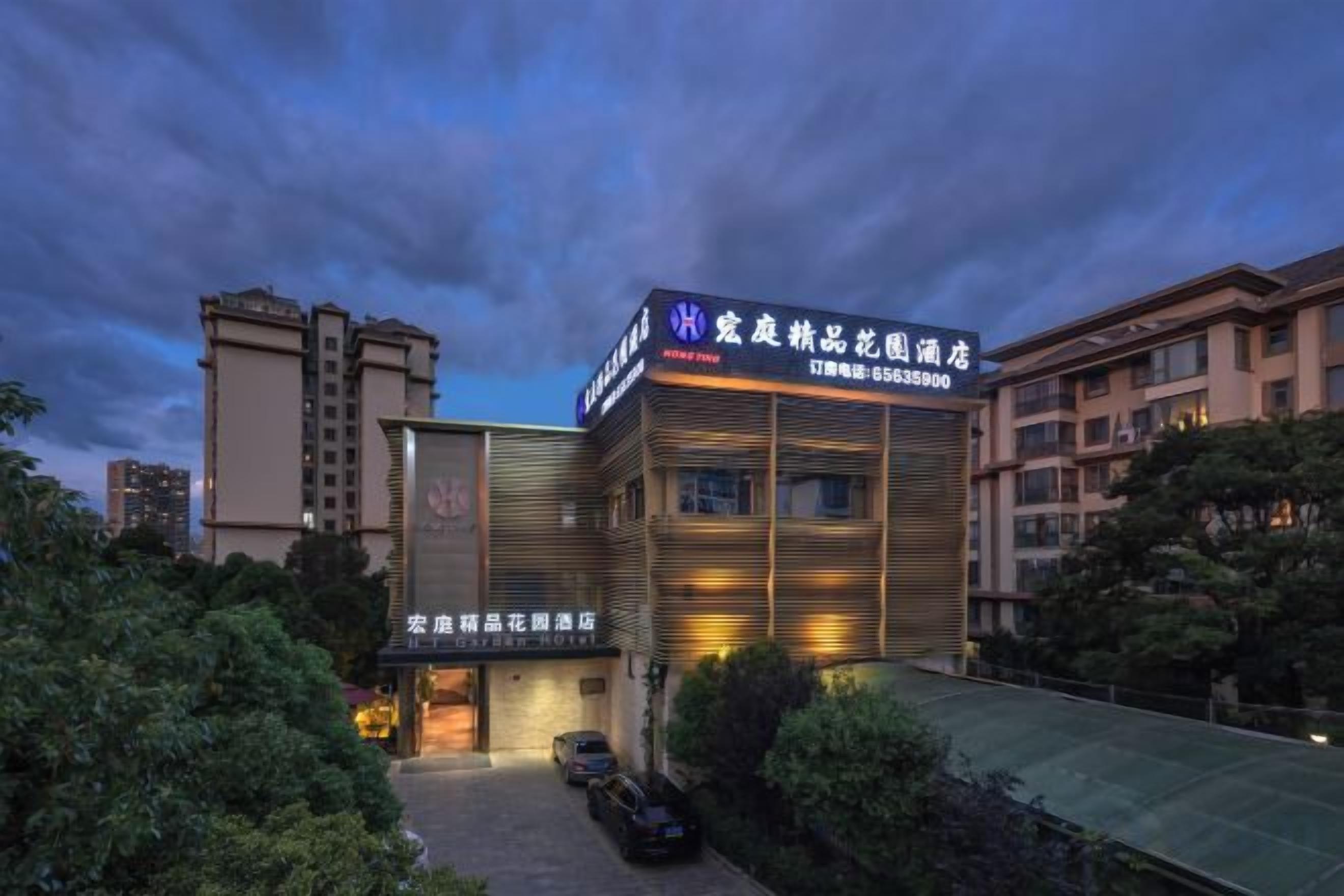 A hotel with a modern facade, signage indicating it is a hotel, and a parking area in front.