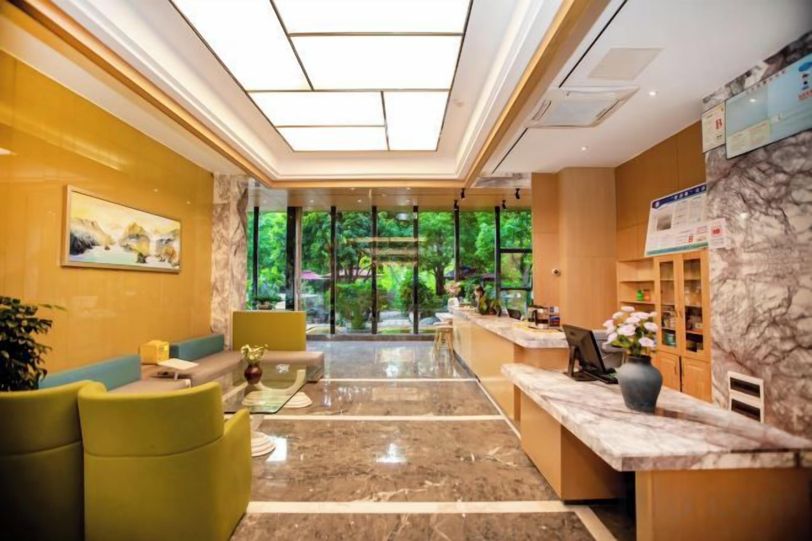 Un hall de hotel con mostrador de recepción, zona de estar y vistas al exterior.
