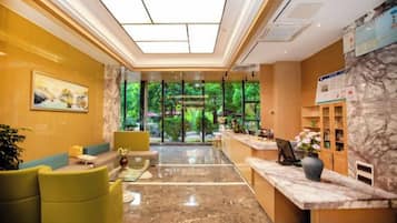 Una hall d'albergo con reception, area relax e vista sull'esterno.