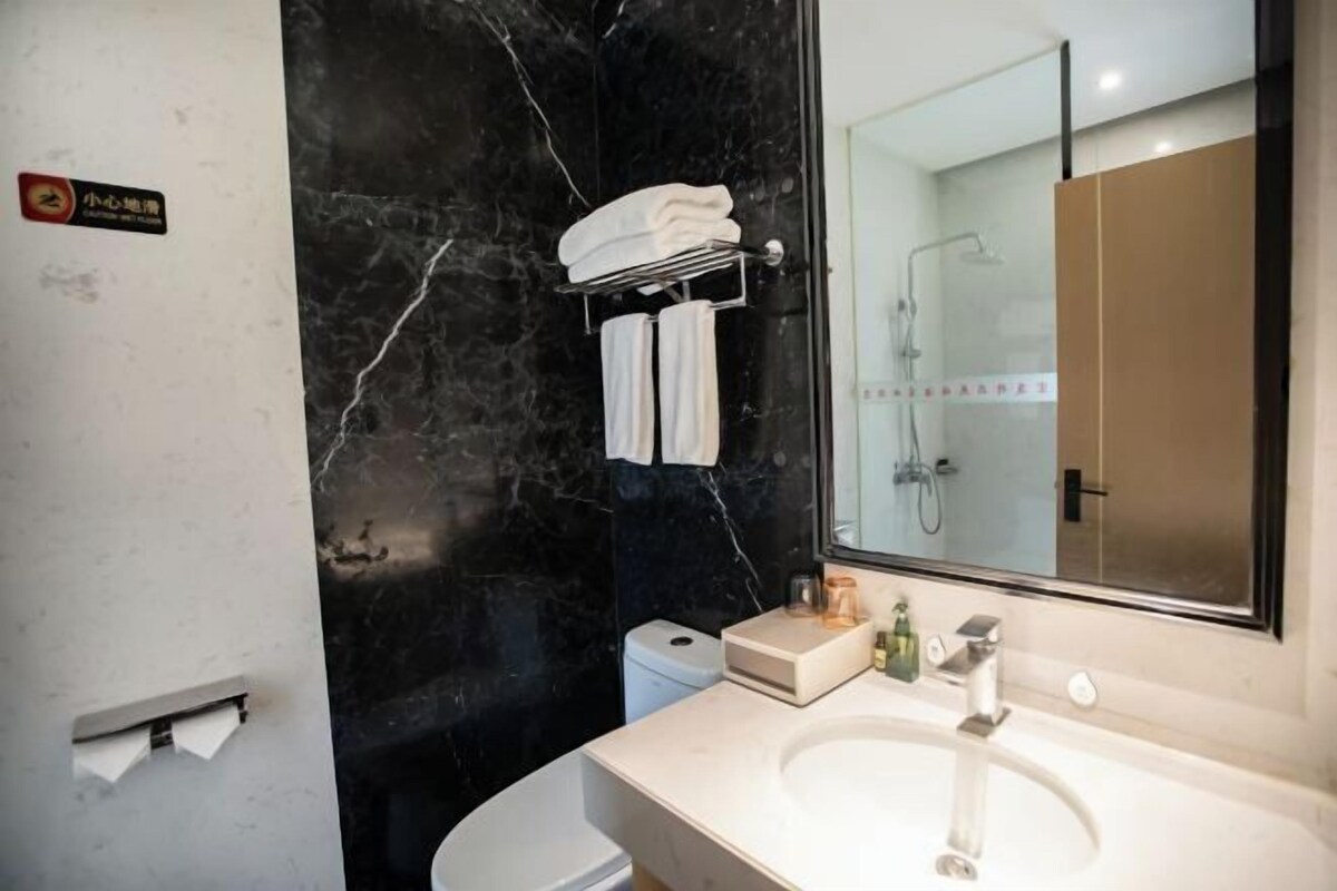 Un baño moderno con pared de mármol, un lavamanos y cabina de ducha de vidrio.