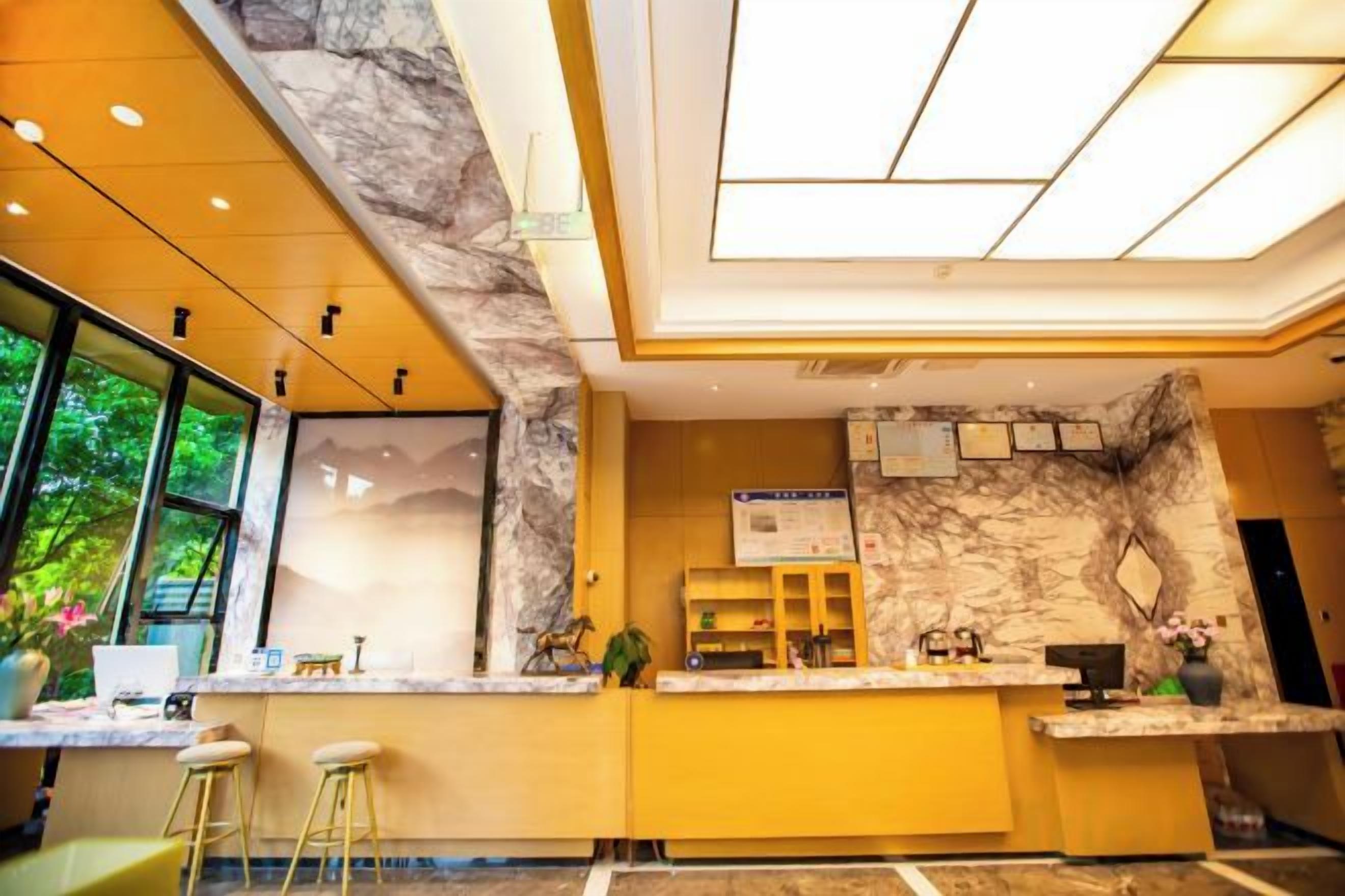 A modern reception area with a marble accent wall, a reception desk, and a large window providing a view of greenery.