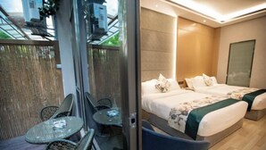 A hotel room with a bed, two chairs, a small table, and a view of the outside. - Hongting Garden Hotel (Kunming)