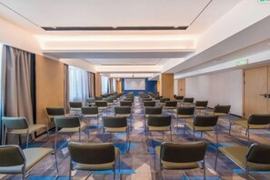 A conference room with rows of chairs, a projector screen, and a carpeted floor. - Hongting Garden Hotel (Kunming)