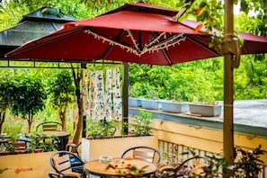Un patio exterior con un paraguas rojo, una mesa redonda y sillas.