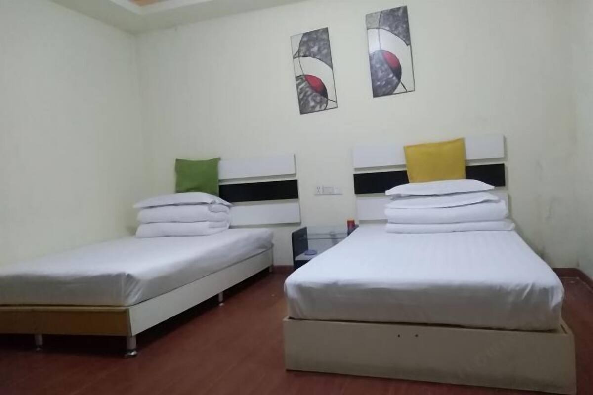 Habitación de hotel con dos camas individuales, cada una con una almohada y una toalla doblada.