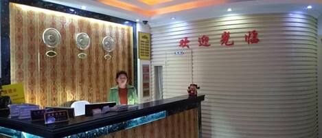 A reception area with a curved reception desk, a receptionist, and a wall with Chinese characters.
