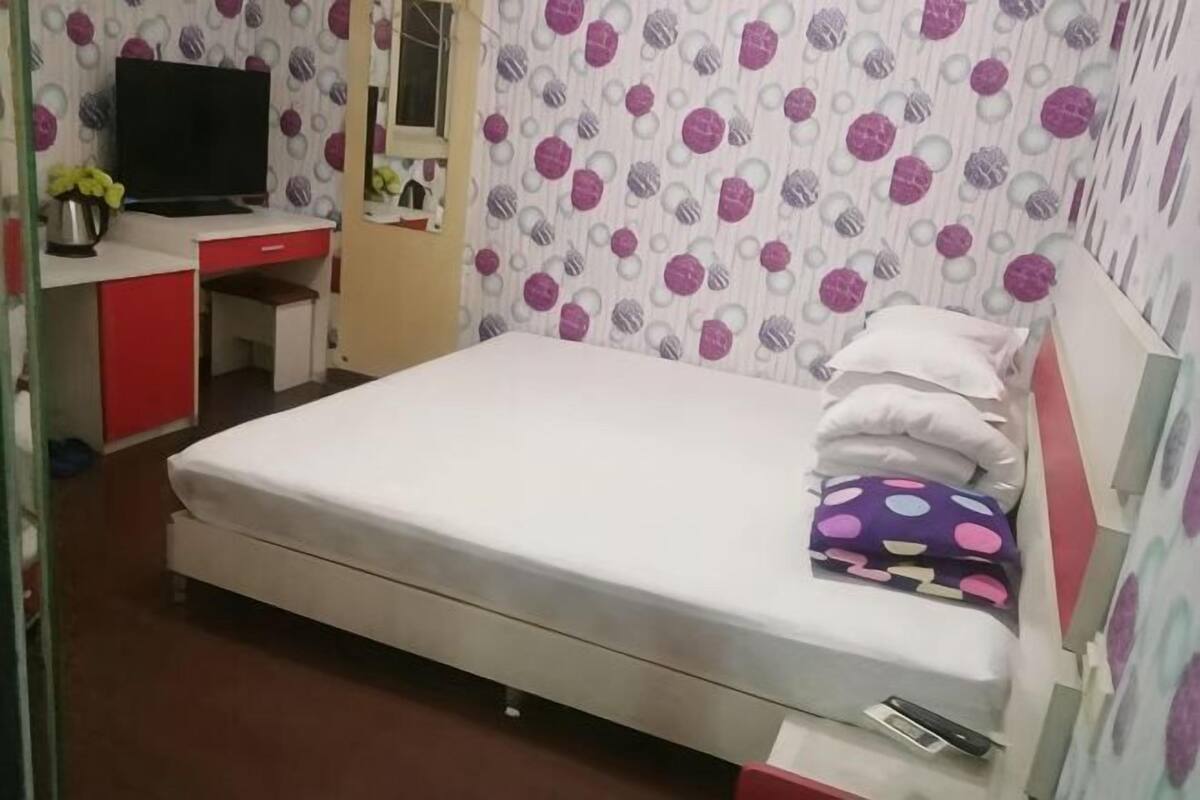 Una habitación con cama, escritorio con silla, televisor y ventana.