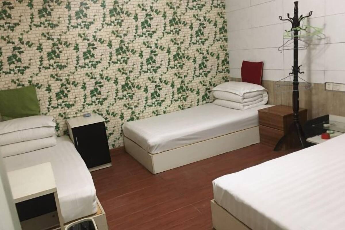 Una habitación con dos camas, un armario, perchero y pared con diseño.