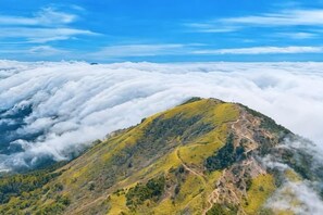 A mountain with a clear sky above and a layer of clouds below. - Hangzhou Shimenxia Hotel Resort (Hangzhou)