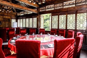 A round table with red chairs in a wooden room with traditional Chinese window designs. - Hangzhou Shimenxia Hotel Resort (Hangzhou)
