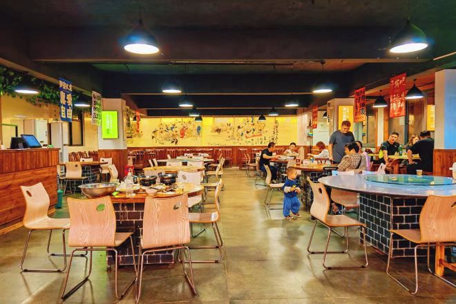 Un restaurante con varias mesas y sillas, una barra y algunas personas cenando.