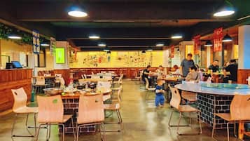 Un restaurante con varias mesas y sillas, una barra y algunas personas cenando.