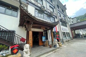 A traditional building with a tiled roof entrance, a signboard, and a statue.