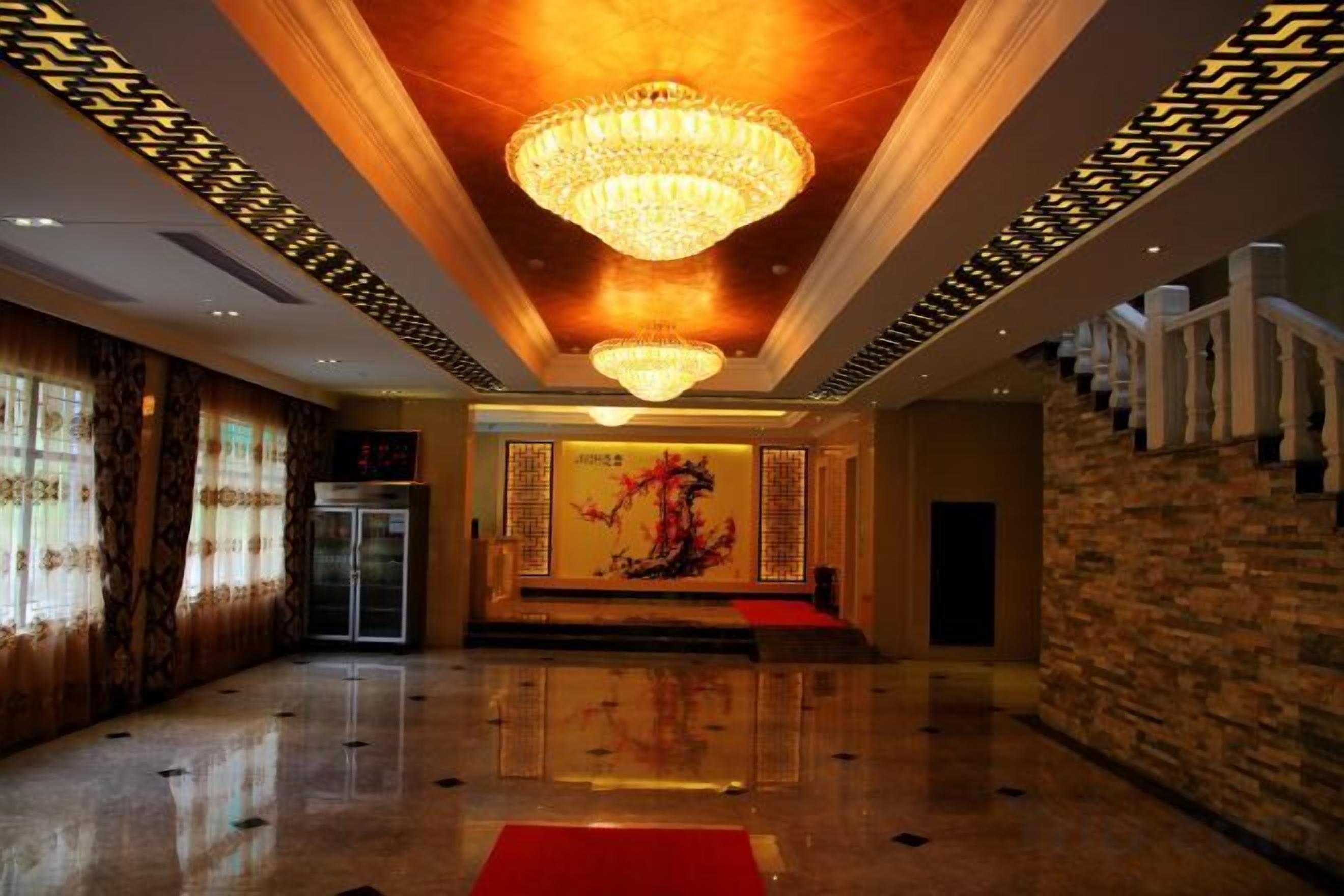 Un hall amplio con candelabro, alfombra roja y escalera.