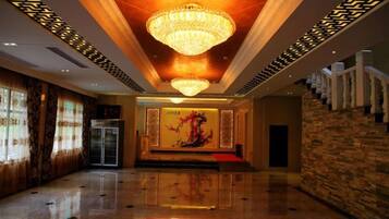 Un hall amplio con candelabro, alfombra roja y escalera.