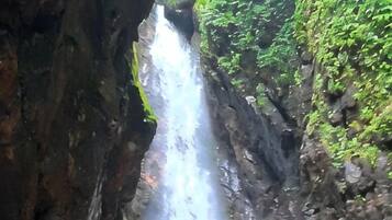 A waterfall cascading down a rocky cliff surrounded by greenery.
