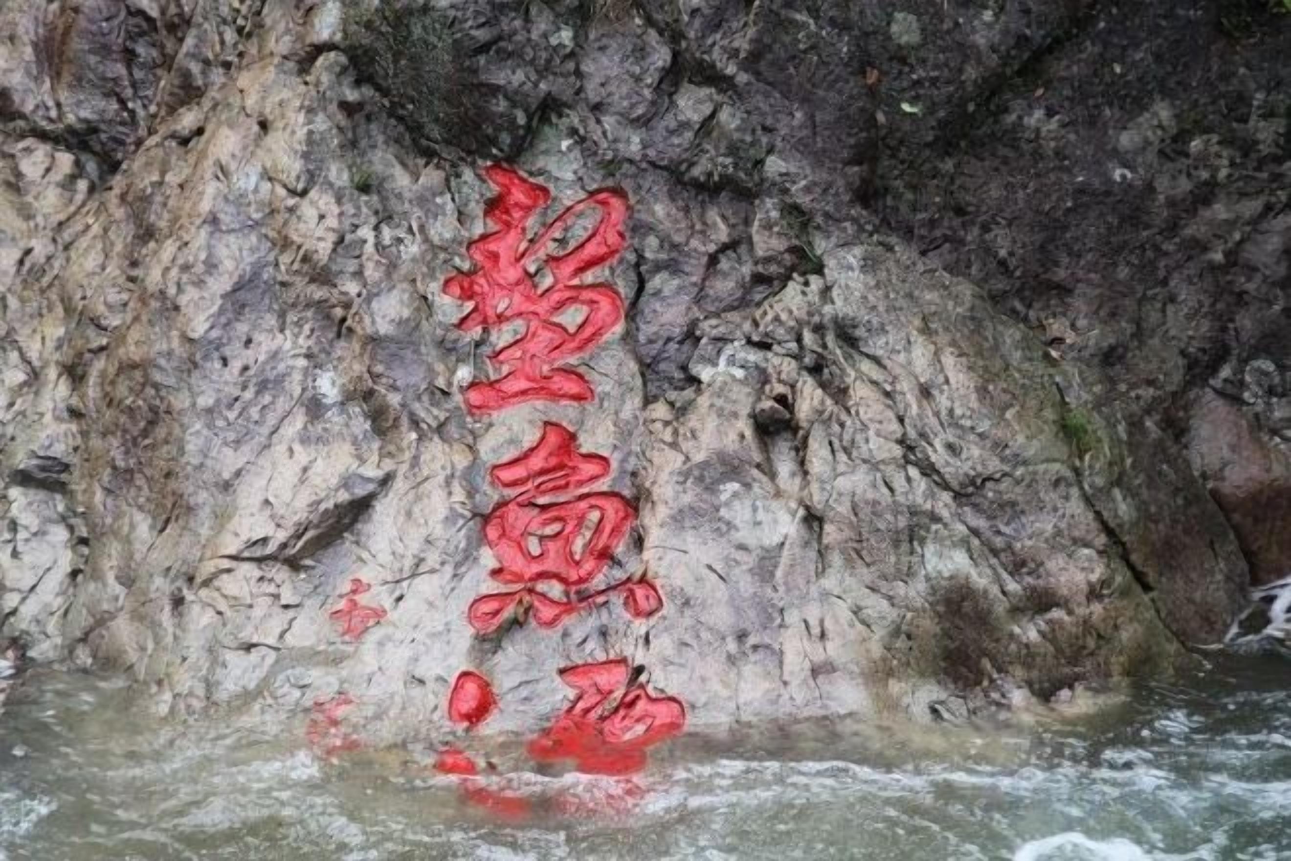 Eine Höhle mit roter Schrift auf der Wand und einem Gewässer im unteren Bereich.
