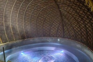 Un bain à remous doté d’un plafond incurvé et d’une sortie de vapeur.