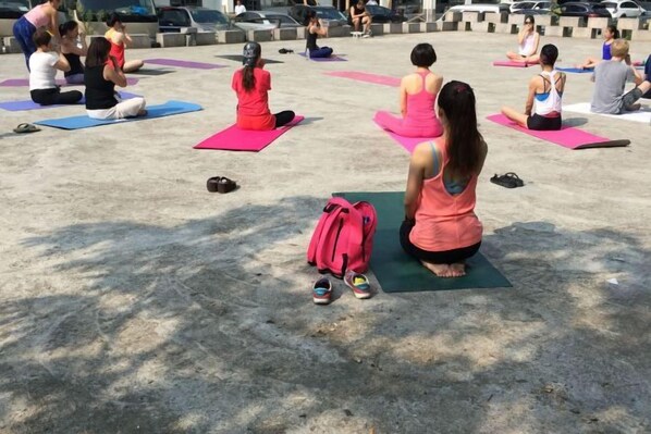 A group of people sitting on yoga mats in an outdoor setting.