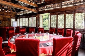 A traditional wooden dining room with round tables and red chairs, large windows with intricate designs, and a wooden ceiling. - Hangzhou Shimenxia Hotel Resort (Hangzhou)