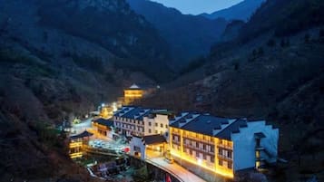 Un hotel con varias construcciones, un patio central y montañas al fondo.