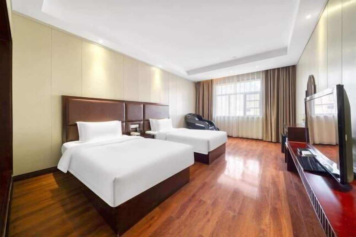 Habitación de hotel con dos camas, televisión y sillón de masajes.