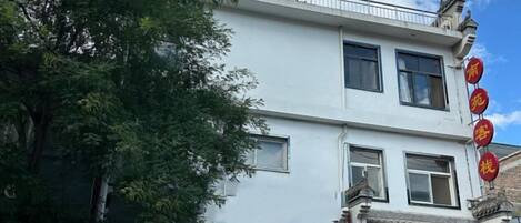 Un edificio de dos pisos con elementos arquitectónicos tradicionales, que incluye un balcón y un cartel con caracteres chinos.
