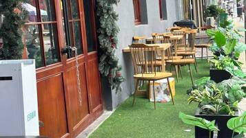 A courtyard with wooden tables and chairs, a small garden area with artificial grass, and potted plants.