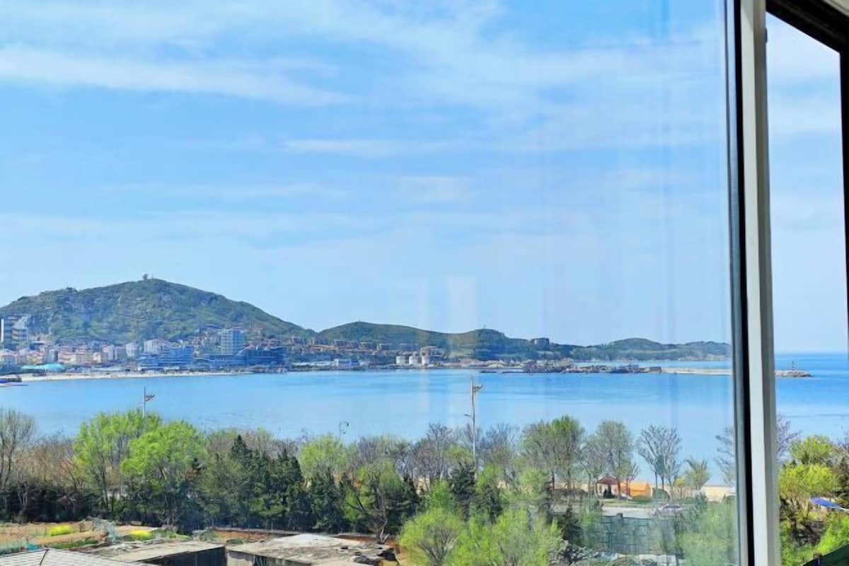 A coastal view with a mountain, buildings, and a clear sky.