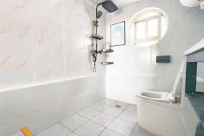 Une salle de bain avec une baignoire, des toilettes, une douche et une petite fenêtre.