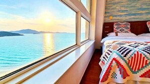 A room with a bed, a window with a view of the sea, and a patterned blanket. - Weihai Shanhai Boutique Homestay (Weihai)
