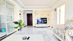 A living room with a sofa, a coffee table, a TV, and a potted plant. - Weihai Shanhai Boutique Homestay (Weihai)
