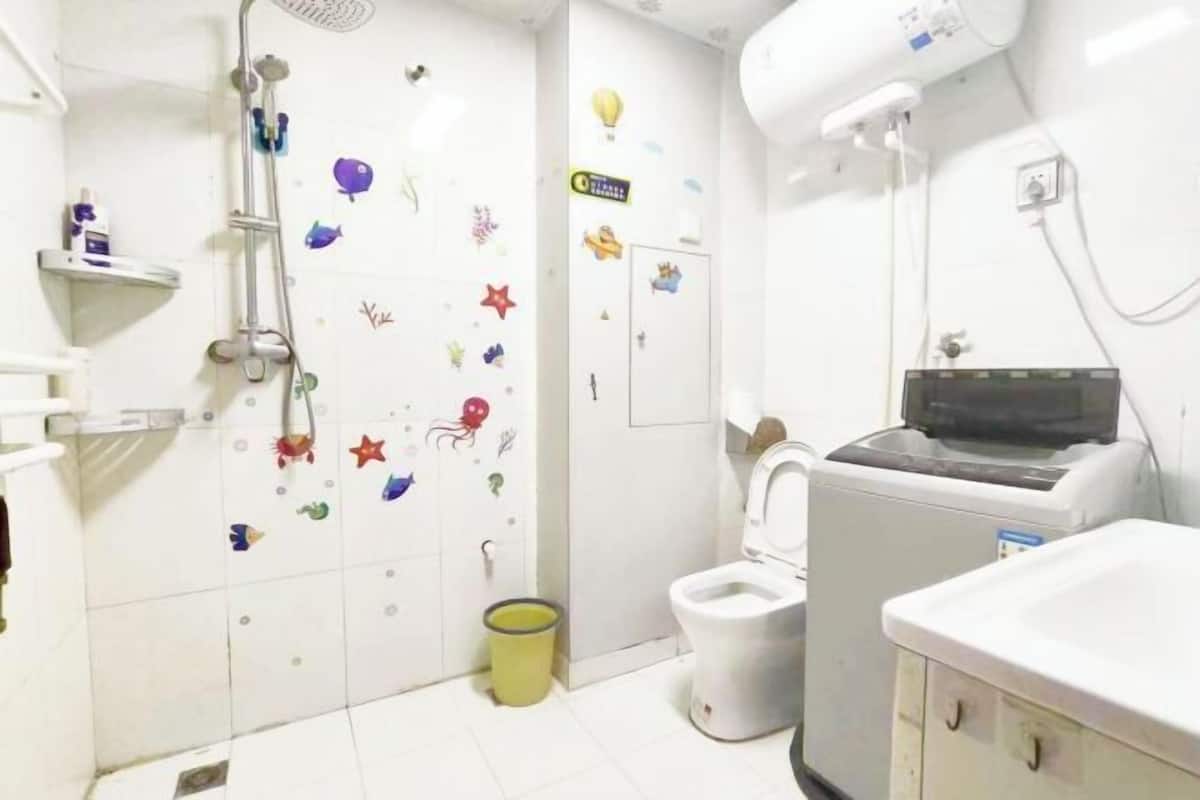 A bathroom with a shower, toilet, and a washing machine.