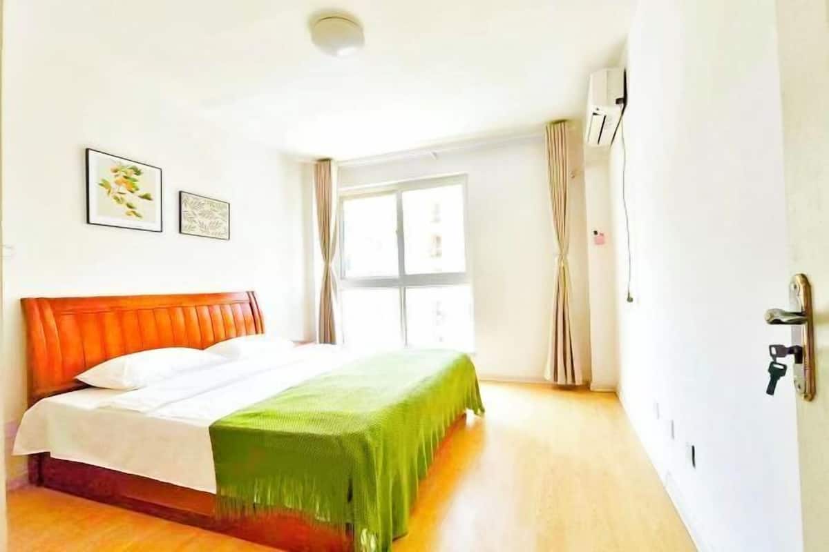 A bedroom with a bed, a window, and a door.