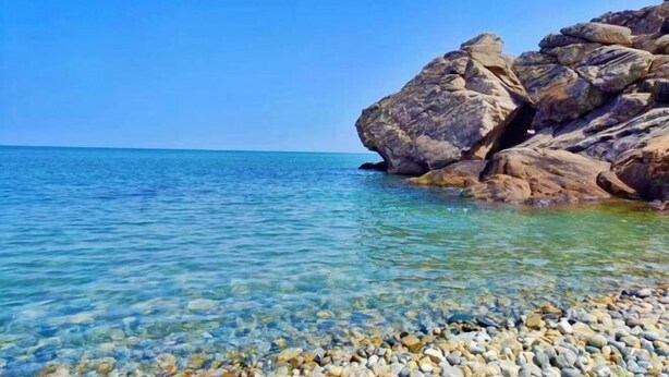 A rocky shoreline with clear water and pebbles. - Weihai Shanhai Boutique Homestay (Weihai)