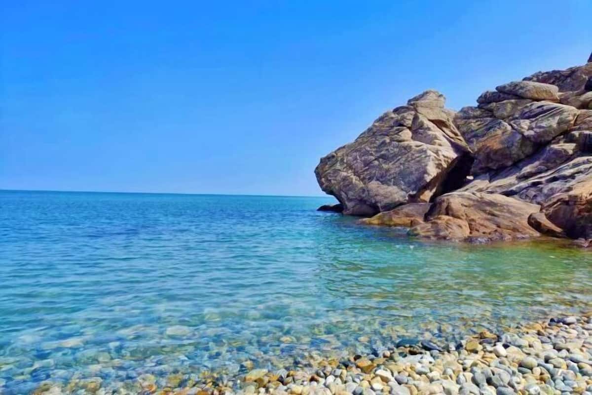 A rocky shoreline with clear water and pebbles.