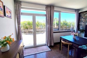 A room with a sliding glass door, a dining table with chairs, a vase with flowers, and a stone wall. - Weihai Shanhai Boutique Homestay (Weihai)