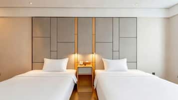 A hotel room with two beds, a modern headboard, bedside lamps, and a small table.