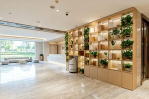 A modern reception area with a wooden bookshelf, seating, and a large window. - Easy Go Inn (Shanghai Hangtou Hunan Highway Store) (Shanghai)