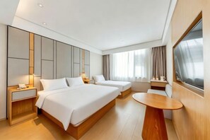 Ein modernes Hotelzimmer mit zwei Betten, einem hölzernen Nachttisch, einem runden Holztisch und einem großen Fenster mit Vorhängen.